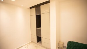 Ein Zimmer mit eingebautem Kleiderschrank, einem kleinen Hocker und einem grünen Handtuch.