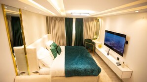 Ein modernes Hotelzimmer mit einem großen Bett, einem Fernseher, einem Schreibtisch und einem Spiegel.