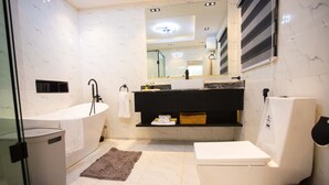 Ein modernes Badezimmer mit freistehender Badewanne, Toilette, Waschtisch mit Spiegel und Duschbereich.