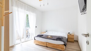A modern bedroom with a wooden bed, bedside tables, a TV, and a sliding glass door to the outside.