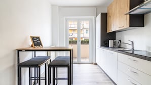 A modern kitchen with a wooden table, two barstools, and a chalkboard with a message.
