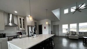 A modern kitchen with a large island, stainless steel appliances, and pendant lighting. - Contemporary all new, entire home perfect for a luxury getaway (Fort Davis)