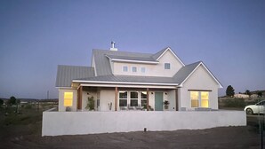 A modern two-story house with a flat roof, large windows, and a covered front porch. - Contemporary all new, entire home perfect for a luxury getaway (Fort Davis)