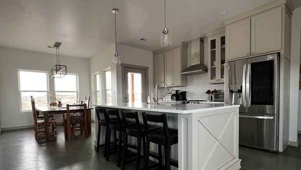 A modern kitchen with a large island, stainless steel appliances, and a dining area with a view. - Contemporary all new, entire home perfect for a luxury getaway (Fort Davis)