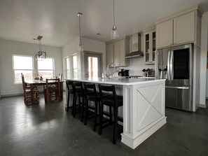 A modern kitchen with a large island, stainless steel appliances, and a dining area with a view.