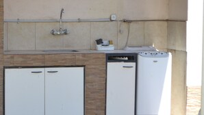 Eine kleine Küche mit Spüle, einem kleinen Kühlschrank und einer Waschmaschine.
