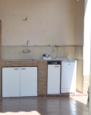 A compact kitchen with a sink, a small refrigerator, and a washing machine.