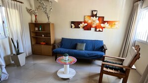 A living room with a blue sofa, a wooden chair, a small round table, and a decorative wall piece.