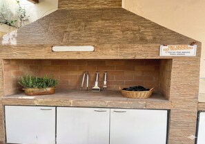Une cuisine extérieure dotée d’un mur de fond en pierre, d’un panneau indicateur et d’ustensiles de cuisine.