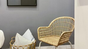 Una silla de mimbre con cojín y un cuadro en la pared.
