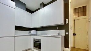 Una cocina moderna con armarios blancos, un microondas integrado y un lavamanos de acero inoxidable.