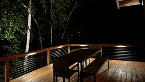 A wooden deck with a table and chairs, surrounded by trees and a railing. - Modern Mountain Chalet Near Storyland & Summer Fun (Intervale)