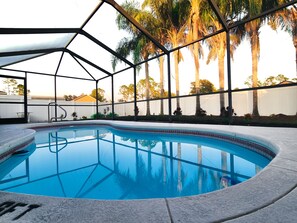 A swimming pool with a clear blue water surface, surrounded by a metal fence and palm trees. - Tropical Paradise - Private Heated Pool, Screened Lanai, No Cleaning Fee (Lakeland)