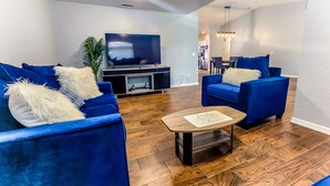 A modern living room with two blue sofas, a wooden coffee table, and a flat-screen TV on a stand. - Tropical Paradise - Private Heated Pool, Screened Lanai, No Cleaning Fee (Lakeland)