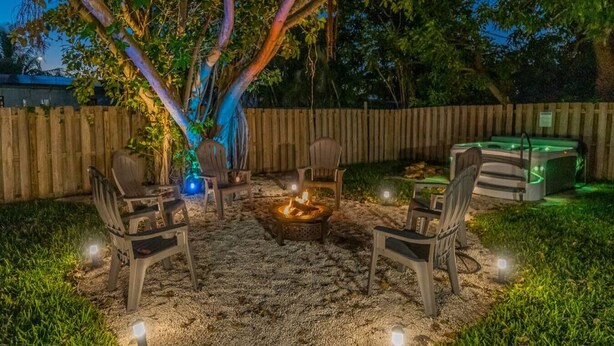 An outdoor seating area with a fire pit, surrounded by chairs, under a tree with illuminated branches. - So Flo Getaway, * Close to beach! * (Fort Lauderdale)