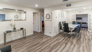 A modern living room with a dining area, wooden flooring, a glass coffee table, and a large mirror. - So Flo Getaway, * Close to beach! * (Fort Lauderdale)