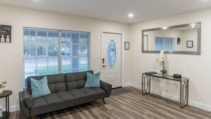 A living room with a grey sofa, a glass coffee table, and a large window with blinds. - So Flo Getaway, * Close to beach! * (Fort Lauderdale)
