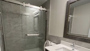 A modern bathroom with a glass-enclosed shower, a white toilet, and a vanity with a sink and mirror. - Finest BR Free Parking/Wifi TV Shared Suite (Milton)