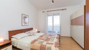 Et soveværelse med en træseng, et natbord, en sengebord, et vindue med udsigt og en dør til en balkon.