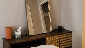A hotel room with a bed, a dresser with a mirror, a tissue box, and a candle.