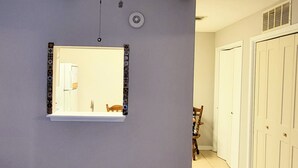 A room with a ceiling fan, a large mirror, and a door leading to a hallway with a tiled floor.