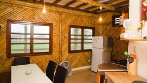 A rustic kitchen with wooden walls, a white refrigerator, and a dining area with a table and chairs. - Cabins in front of the Beach -  Playas - Ecuador (Playas)