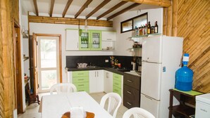A compact kitchen with green and white cabinets, a white refrigerator, and a dining table with chairs. - Cabins in front of the Beach -  Playas - Ecuador (Playas)