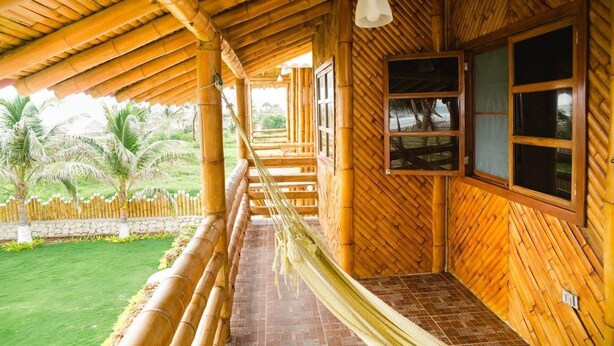 A wooden structure with a bamboo roof, a hammock, and a view of palm trees. - Cabins in front of the Beach -  Playas - Ecuador (Playas)