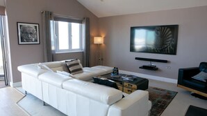 Un soggiorno moderno con un divano in pelle bianca, un tavolino da caffè, una TV e un tappeto decorato.
