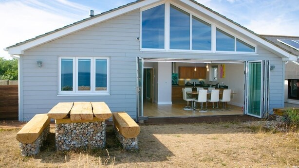 Una casa moderna con un patio, un'area pranzo e una cucina visibile attraverso la porta aperta.