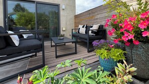 A patio with a sofa, a coffee table, and potted plants. - Goldfinch House - Scandinavian Modern Near Beaches (Seattle)