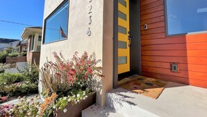 A modern building with a beige facade, a yellow door, and a window reflecting the sky. - Goldfinch House - Scandinavian Modern Near Beaches (Seattle)