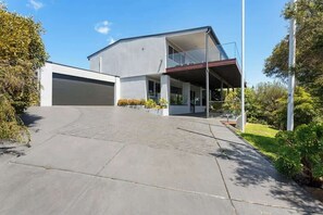 A modern two-story house with a garage, a covered outdoor area, and a paved driveway.
