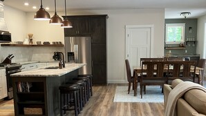 Una cucina moderna con isola centrale, sgabelli da bar e luci a sospensione.