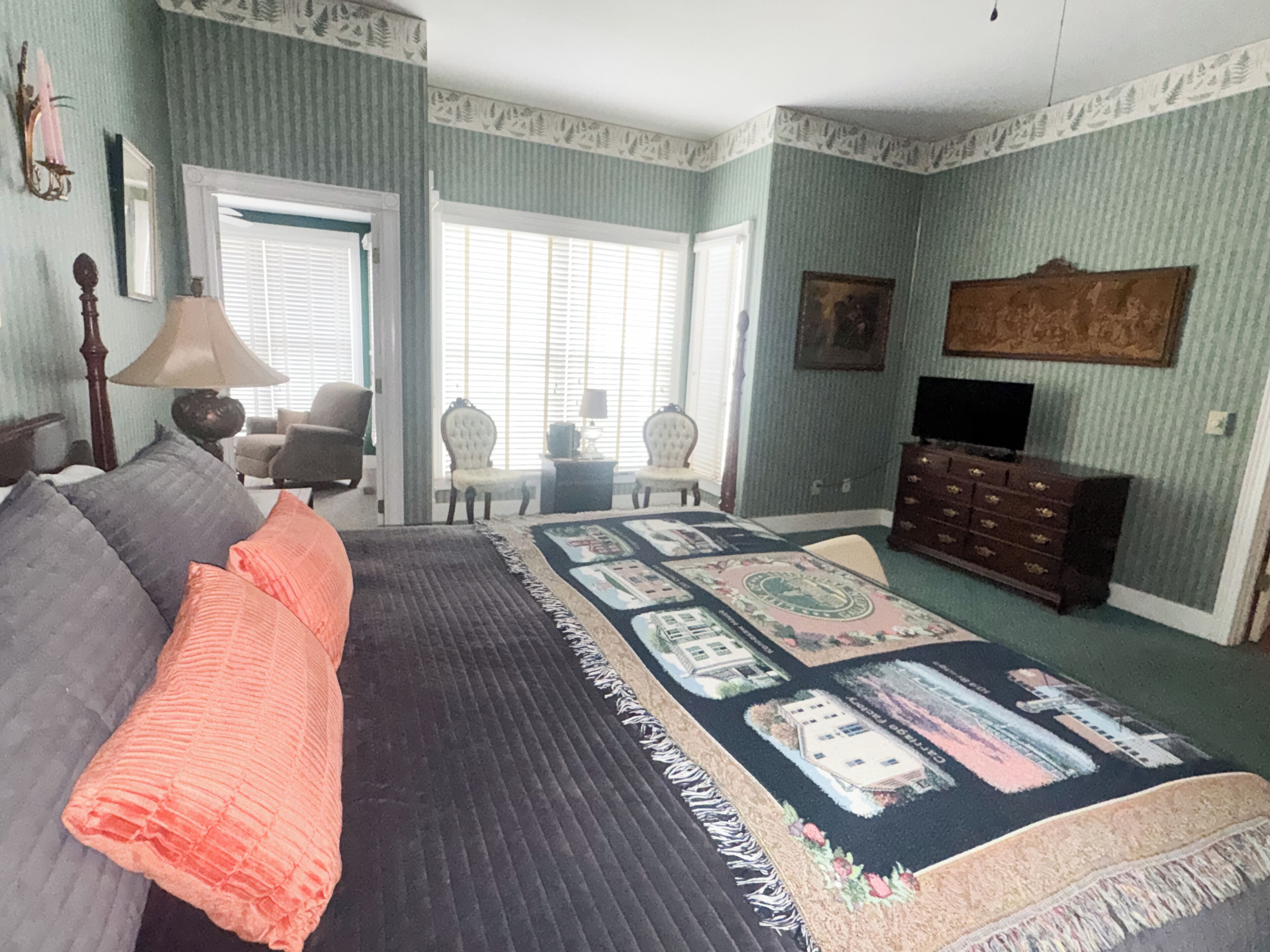 A bedroom with a bed, a dresser, a television, and a window.