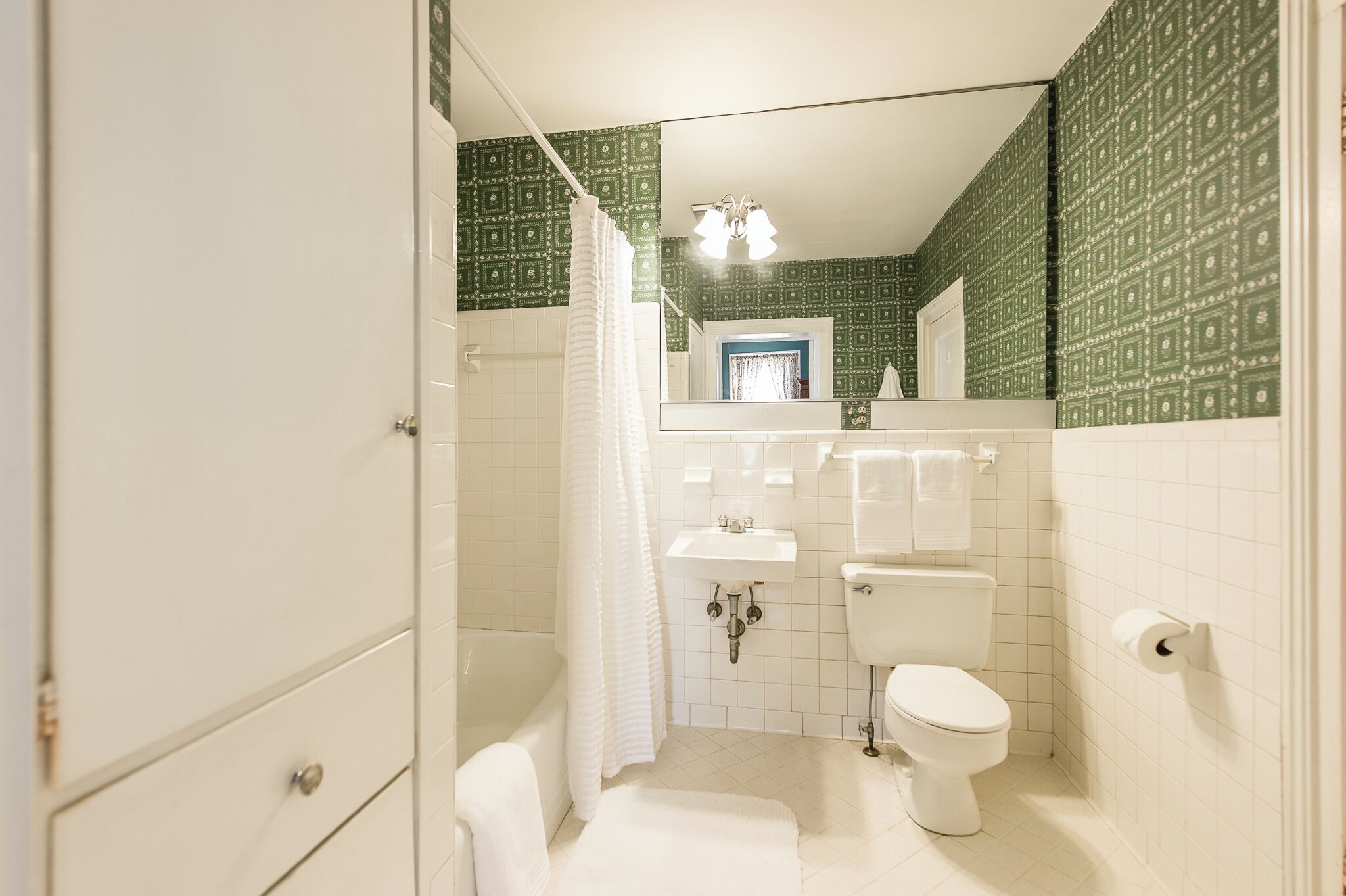 A bathroom with a white bathtub, a toilet, a sink, and a mirror.