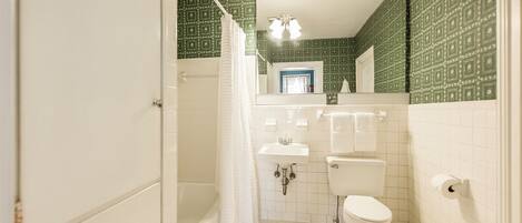 A bathroom with a white bathtub, a toilet, a sink, and a mirror.