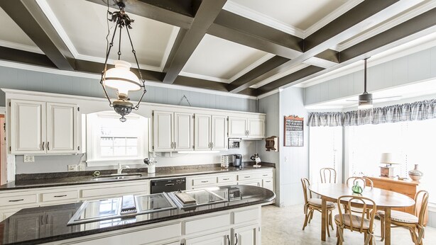 A spacious kitchen with white cabinets, a granite countertop, and a dining area with a wooden table and chairs.
