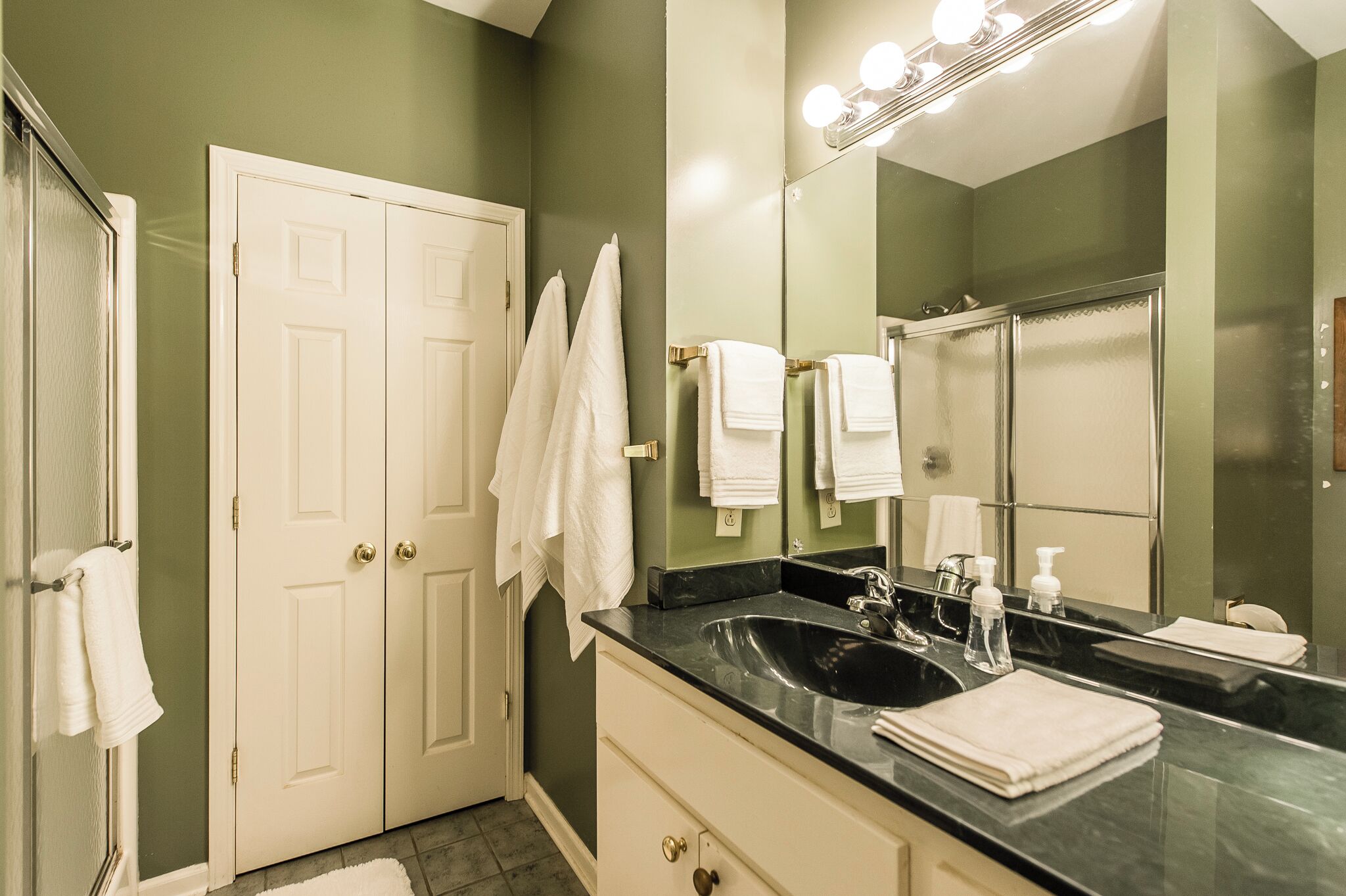 Une salle de bain avec un double lavabo, un grand miroir et deux serviettes blanches accrochées au mur.