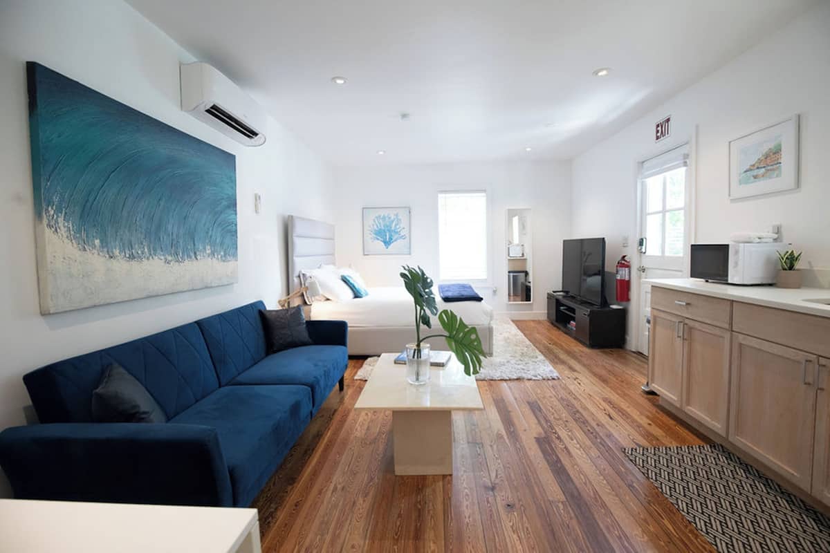 Una sala moderna con un sofá azul, una mesa de centro y un cuadro abstracto grande.