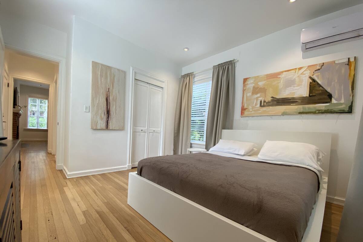 Un dormitorio con una cama grande, un armario, un cuadro y una ventana con cortinas.