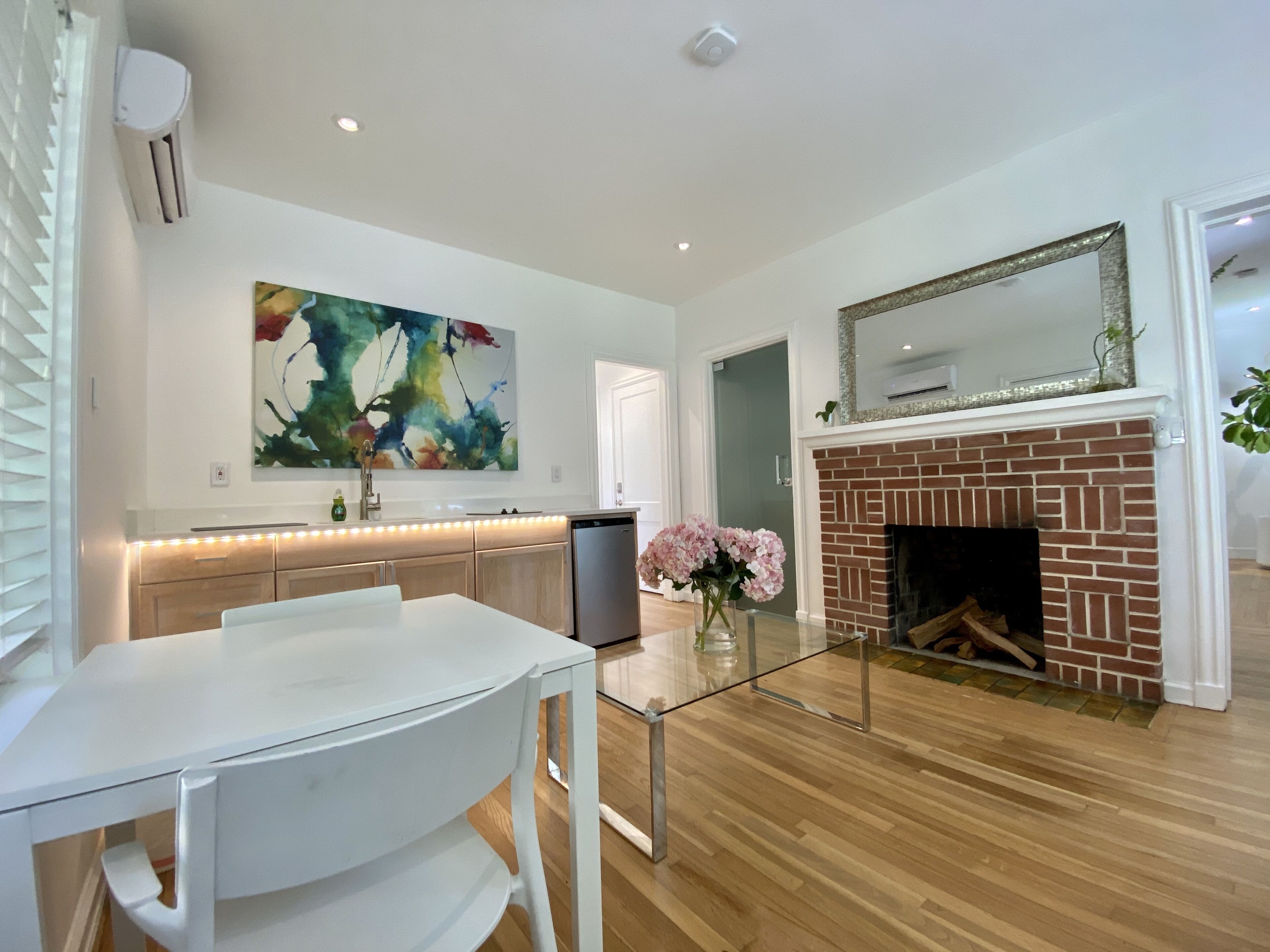 A modern kitchen with a white countertop, a stainless steel refrigerator, and a large abstract painting on the wall.