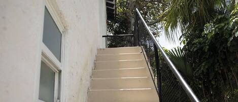 A beige staircase with a metal handrail, leading to a window with a white frame.