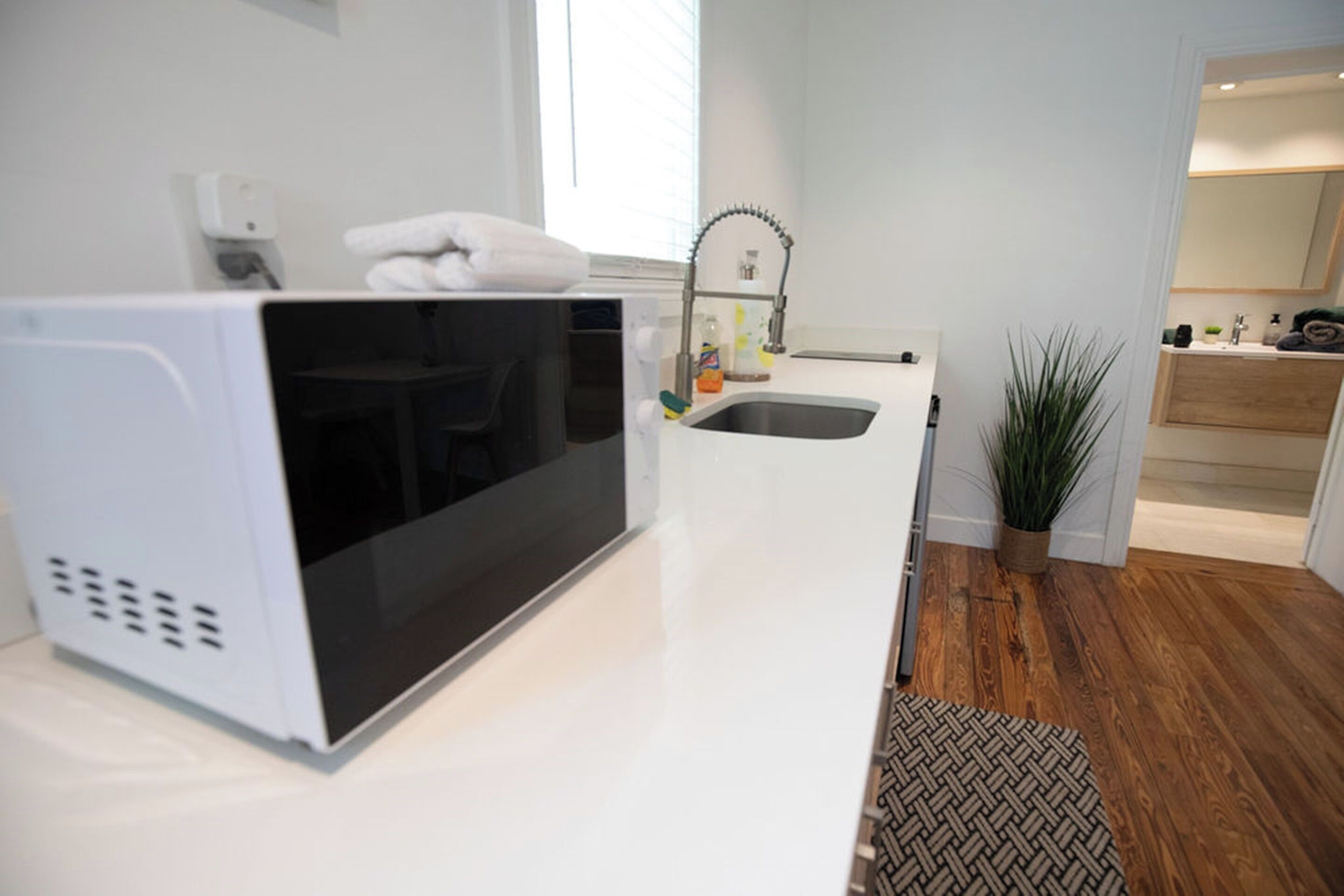 Una cucina moderna con forno a microonde integrato, lavello e una pianta in vaso.