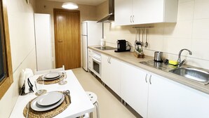 Una cocina compacta con armarios blancos, un lavamanos de acero inoxidable y una puerta de madera.