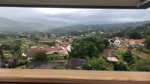 Vista de un pueblo rural con casas, campos y montañas al fondo.
