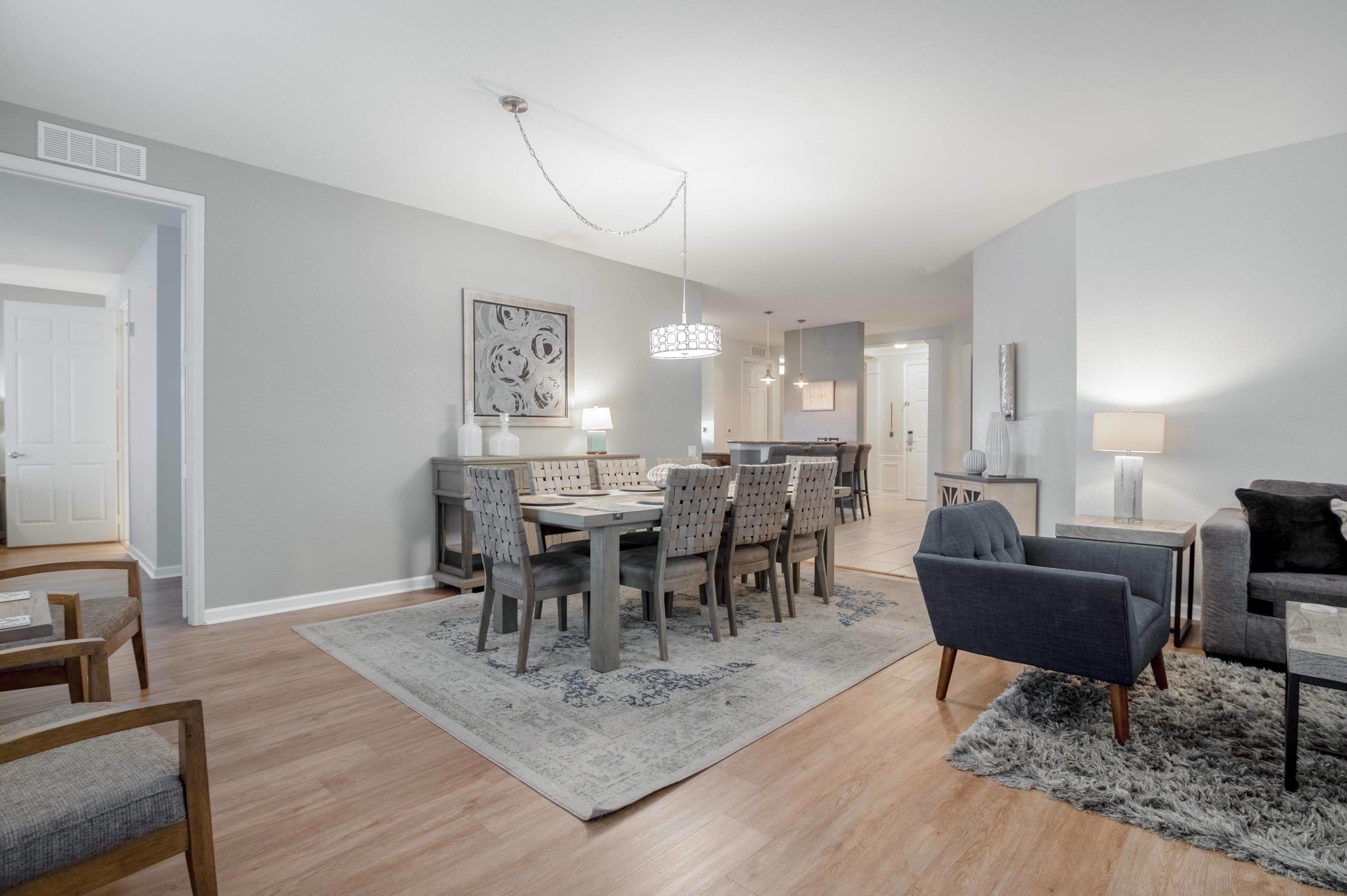 A modern living room with a dining area, featuring a chandelier, a fireplace, and a large window.