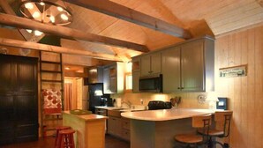 Una cocina con armarios de madera, una isla central con taburetes, un microondas y un letrero de bienvenida.