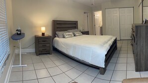A bedroom with a bed, bedside table, lamp, wardrobe, and a chair. - Private 3Bed/3Bath Heated Pool Outdoor Entertainment (Zephyrhills)