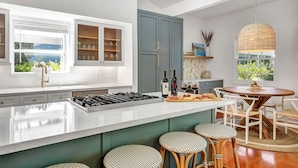 A modern kitchen with a large island, bar stools, and a dining area with a round table. - Your escape to Napa Valley (Yountville)